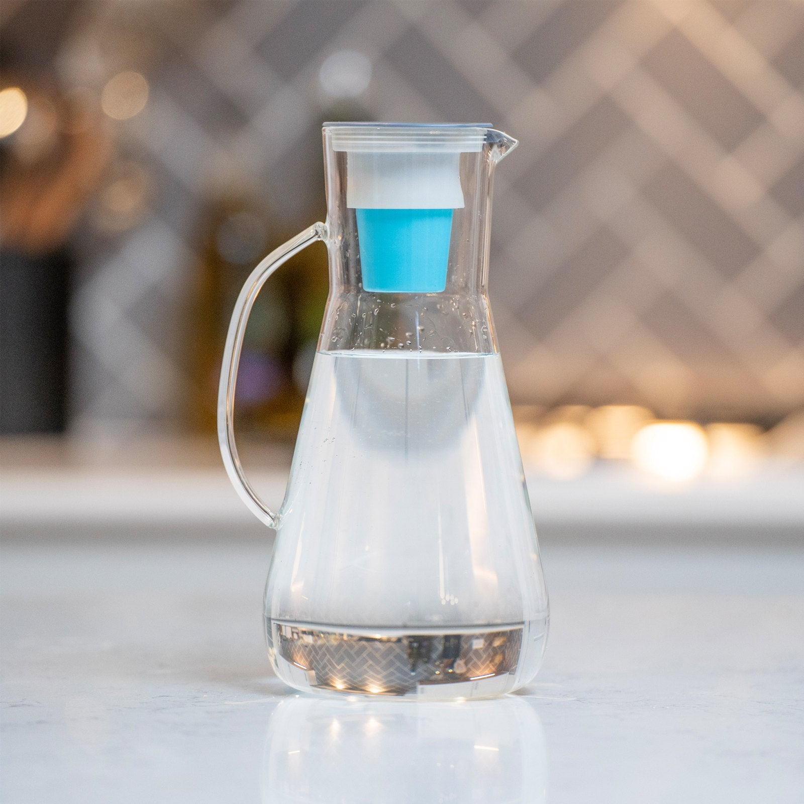 Clear 64-ounce Hydros glass pitcher with handle, light-blue base and lid filter element