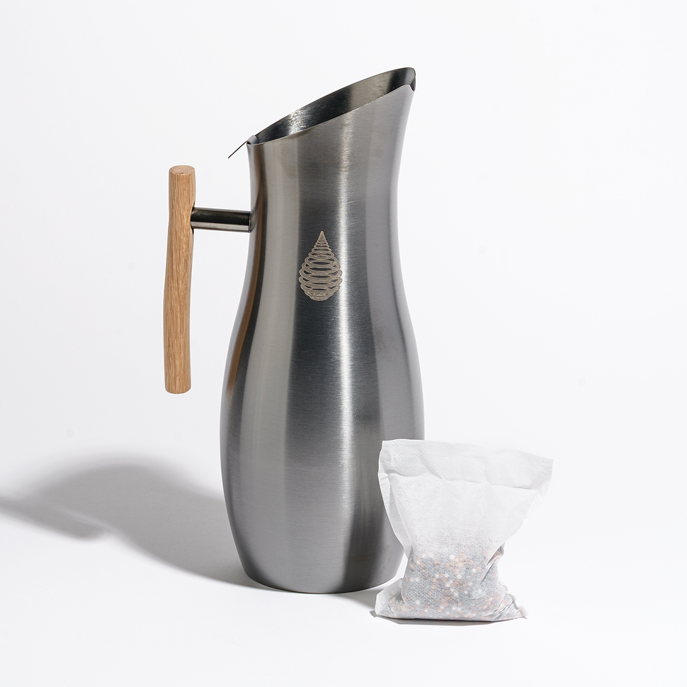 Black Invigorated pH Vitality stainless pitcher with wooden handle beside its separate white infusion pouch